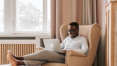 black guy sitting in armchair on a laptop.